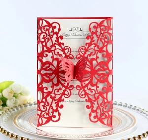 Detail of red laser-cut butterfly invitation card with white insert on elegant tableware