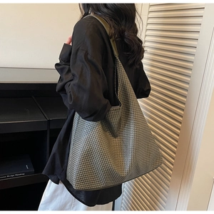 Detailed view of a large grey-green woven tote bag worn on shoulder for commuting