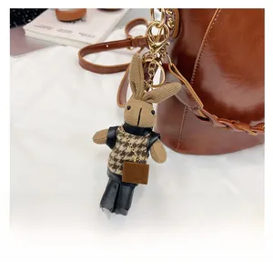 Detail of a brown knit rabbit charm with houndstooth sweater on a leather bucket bag