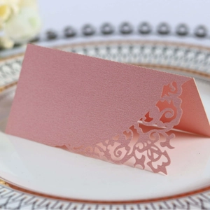Elegant pink laser-cut floral place card for wedding table decor on a ceramic plate