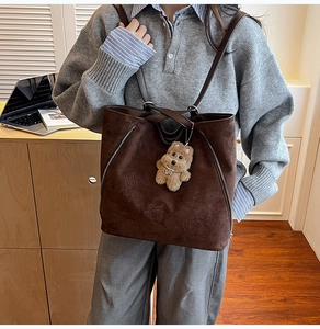 Détail du sac cabas en daim marron foncé avec fermetures latérales et breloque ours
