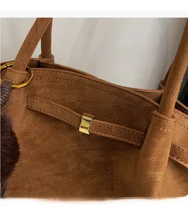 Detail shot of brown lychee texture leather with elegant gold hardware buckle on tote bag