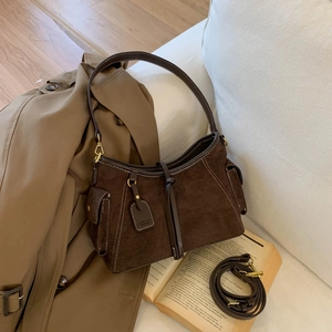Detailed view of dark brown faux suede shoulder bag with retro utility side pockets