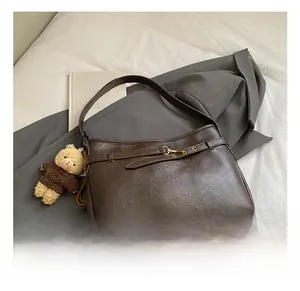 Détails d'un sac bandoulière vintage marron foncé en cuir avec charm ours et boucle en métal