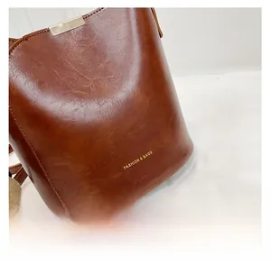 Detail of brown leather bucket bag with gold rectangular clasp and fashion lettering