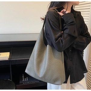 Detail of dark grey woven tote bag on shoulder, showcasing soft leather and large capacity
