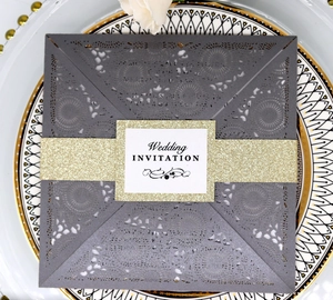 Macro detail of laser-cut mandala wedding invitation with gold glitter band and logo