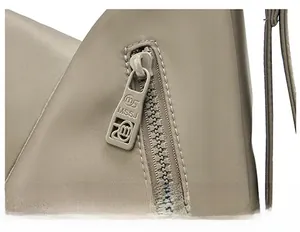 Close-up of a smooth custom metal zipper on a taupe minimalist nylon tote bag