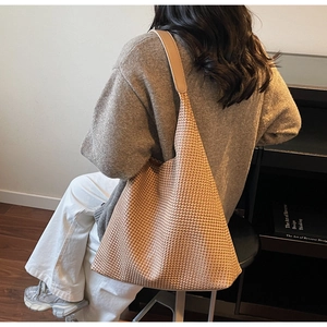 Detail of light brown woven tote bag showing fine textured pattern and wide shoulder strap