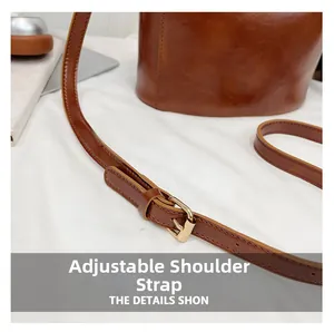 Detailed close-up of the adjustable brown leather shoulder strap with gold metal buckle