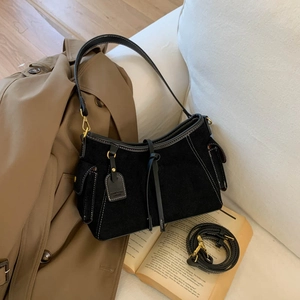 Detail of vintage black suede shoulder bag with gold hardware and extra strap