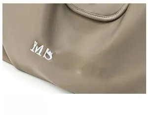 Detailed close-up of khaki nylon fabric with white embroidered MSSHIJIA brand logo