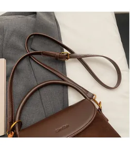 Detail of brown leather and suede stitching bag with gold hardware and logo