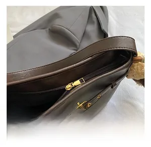 Détails du sac cabas en cuir marron foncé avec fermeture éclair dorée et breloque en peluche