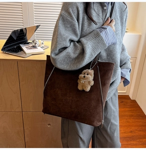 Gros plan sur un sac cabas en daim marron avec fermeture éclair et breloque ours