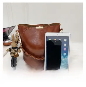 Brown vintage bucket bag with metal buckle, bunny charm and fashion text detail