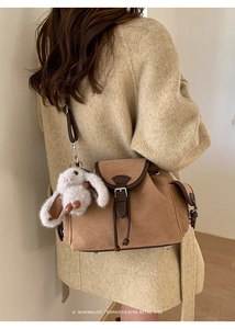 Detailed back view of a retro brown suede crossbody bag with a plush bunny charm