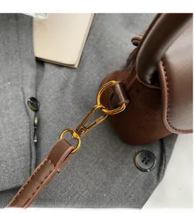 Detail of premium gold-tone swivel clasp on a brown contrast-stitch shoulder bag