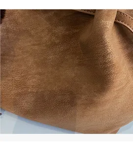 Detailed close-up of brown faux leather bag showing soft pebble texture and stitching