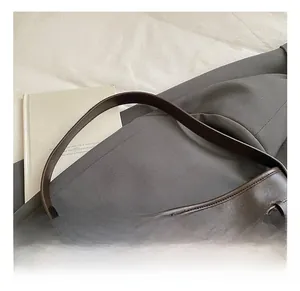 Détail de la bandoulière en cuir marron avec boucle dorée et breloque ours sur le sac