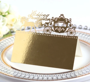 Detail of laser-cut gold mirror wedding place card with elegant royal carriage design