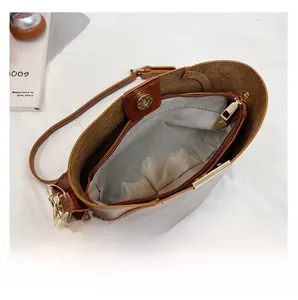 Detail view of brown bucket bag interior with zipper pocket and magnetic snap closure