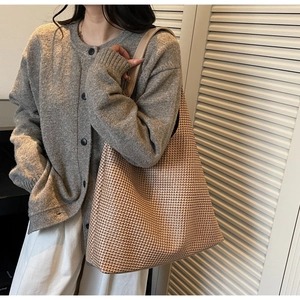 Detail of a large woven tote bag with houndstooth pattern shown on a shoulder