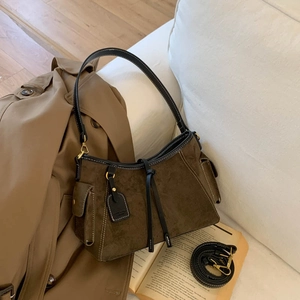 Detailed shot of dark brown suede handbag with side pockets and black leather straps