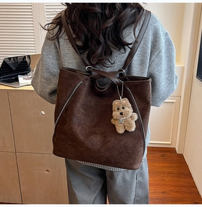 Détail du sac cabas en daim marron foncé avec gaufrage NinAle et breloque ourson