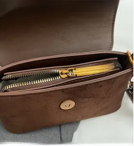 Close-up of soft brown faux suede shoulder bag featuring a metal zipper and magnetic buckle