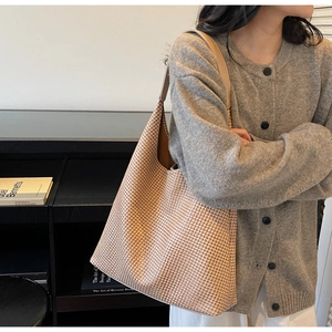Close-up of beige woven tote bag with houndstooth pattern and leather strap