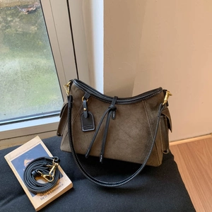 Detailed view of olive green suede shoulder bag with black leather trim and golden hardware