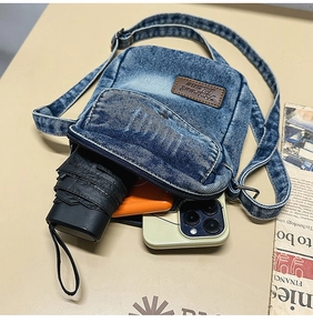 Internal view of denim crossbody bag showing storage capacity for phone and umbrella