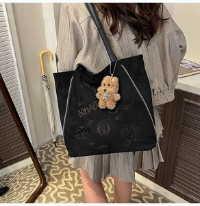 Détail du sac cabas en daim noir avec imprimé dessin animé et breloque ours en peluche