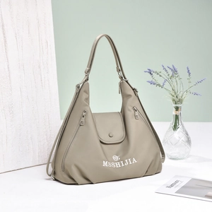 Close-up of light khaki nylon tote bag showing brand logo and side zipper details