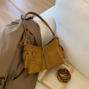Detail of a brown suede hobo bag with side pockets and knot decor on white sofa