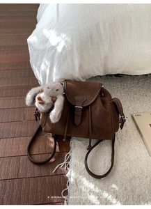 Close-up of retro dark brown suede bucket bag with a cute plush rabbit charm