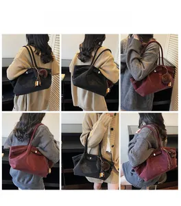 Detail view of large suede tote bags in black and burgundy with furry pompom charms