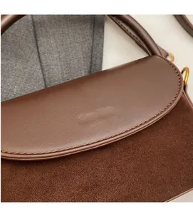 Detail of brown contrast textures on a beaded handbag with brand logo stamping