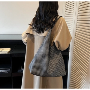 Detailed close-up of the houndstooth weave fabric and black leather shoulder strap on a tote bag