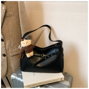 Détail du sac hobo en cuir noir avec boucle dorée et pendentif ours en peluche mignon