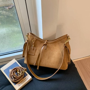 Close-up of caramel brown suede shoulder bag with drawstring detail and texture