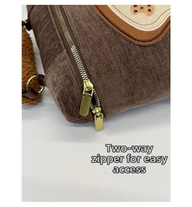 Detail of two-way golden metal zippers on brown corduroy bag with paw embroidery