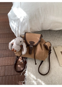 Detail of retro brown suede backpack featuring leather trim and plush rabbit charm