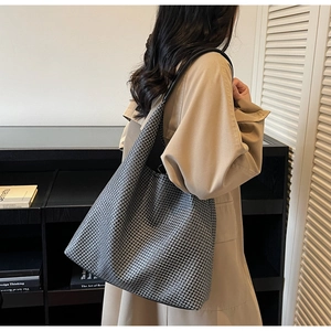 Hobo tote bag with black and white woven texture and leather strap shown on shoulder