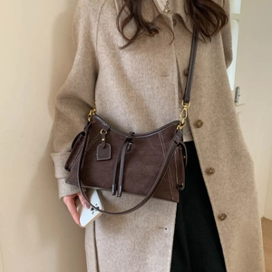 Detail of vintage brown suede shoulder bag with contrast stitching on an elegant outfit