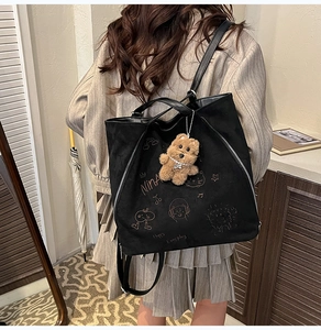 Détail du sac en daim noir avec graffitis Nina dorés et breloque ours mignonne