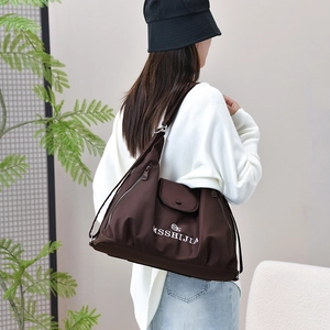 Detail of coffee brown tote bag with white MSSHIJIA logo and adjustable strap closure