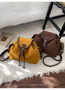 Detail of vintage drawstring bucket bags in yellow and brown suede with leather trim