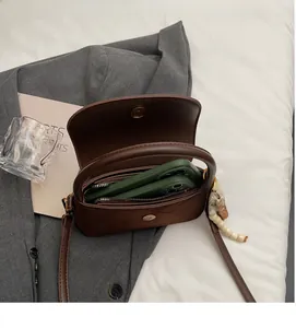 Brown frosted crossbody bag with wooden beads showing interior space for two smartphones